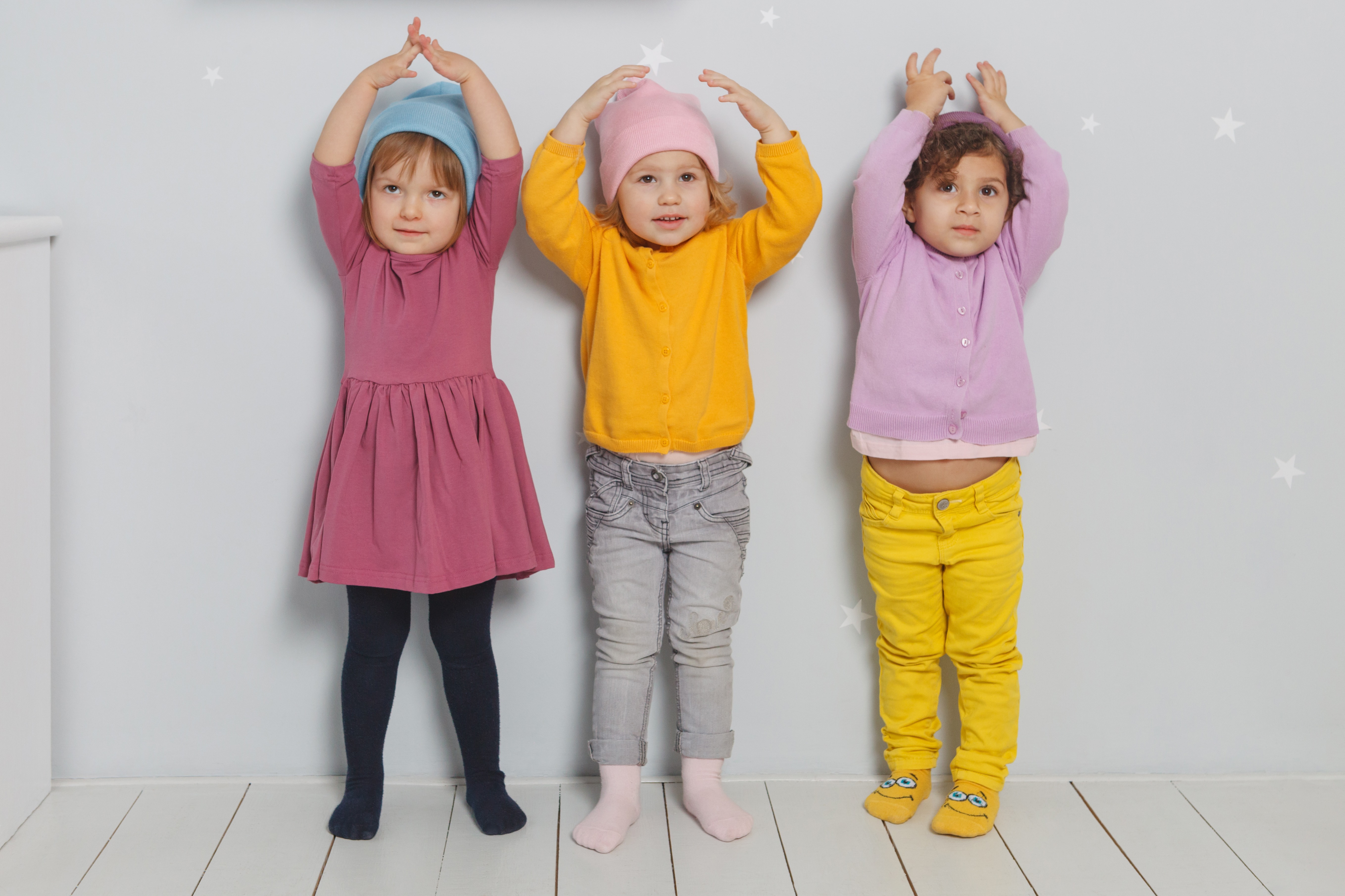 カラフルな服を着て手を上げる3人の子どもたち
